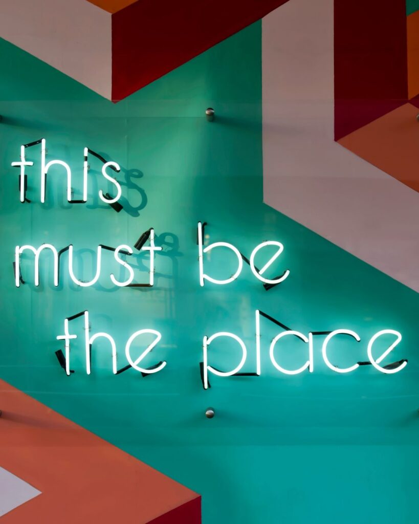 A light banner on a wall "of this must be the place". Photo taken by Tim Mossholder